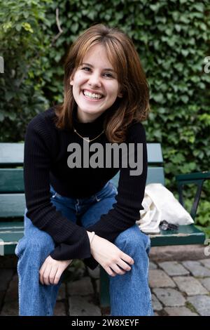 Portrait of happy young woman sitting on bench at park Stock Photo