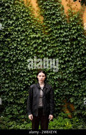 Portrait of young woman standing in front of hedge at park Stock Photo