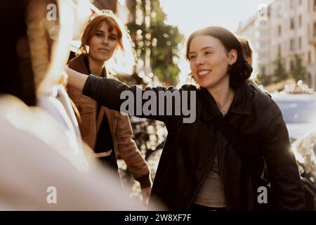 Smiling young woman talking with female tourist friends in city Stock Photo