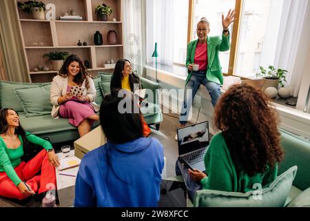 Businessman with hand raised talking with colleagues during meeting at office Stock Photo