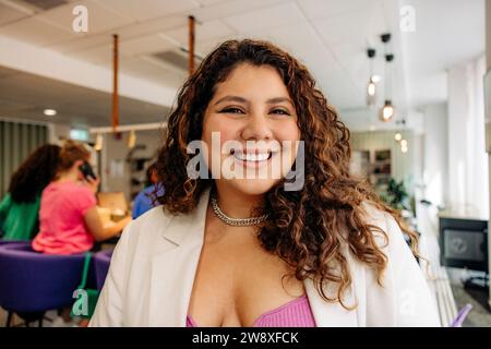 Portrait of happy young businesswoman with curly hair at office Stock Photo