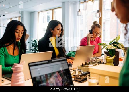 Businesswomen working together on laptops at desk in office Stock Photo