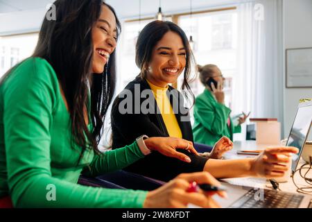 Happy female business colleagues discussing over laptop at office Stock Photo