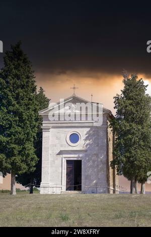 Chapel Capella della Madonna di Vitaleta in Val d' Orcia, Tuscany, Italy at in the Early Morning with Cypress Trees in a Dramatic Mood in september Stock Photo