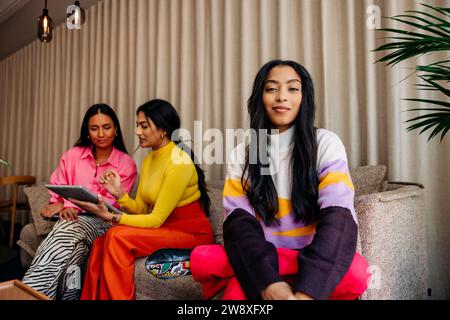 Portrait of female entrepreneur with colleagues sitting on sofa at office Stock Photo