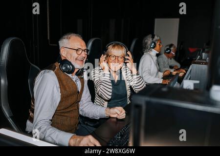 Smiling senior couple playing video game by male and female friends in gaming lounge Stock Photo