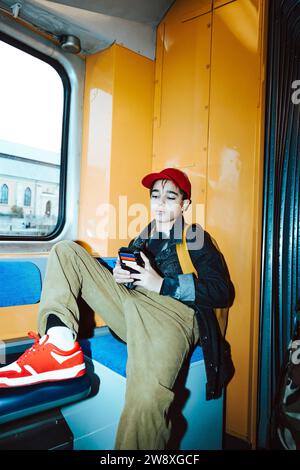Boy using smart phone while sitting in tram during weekend Stock Photo