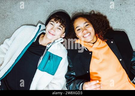 Portrait of smiling boy and girl lying on street Stock Photo