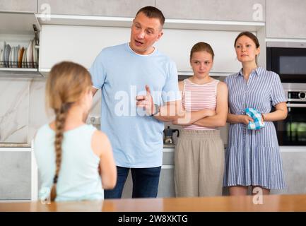 Disgruntled parents and older sister reprimanding tween girl at home ...