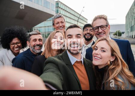 Big group of business people smiling taking a selfie portrait toguether. Crowd of business people looking at camera. Startup corporate team having fun. Happy well dressed executive firm partners. High quality photo Stock Photo