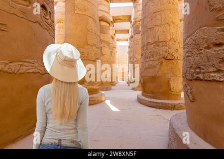Karnak Temple, Luxor, Egypt; December 22, 2023 - A blonde haired woman looks up at columns in the Temple of Karnak, Luxor, Egypt Stock Photo