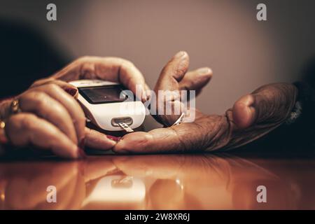 Crop unrecognizable senior woman using glucose monitoring device while measuring blood sugar level of diabetic husband at table Stock Photo