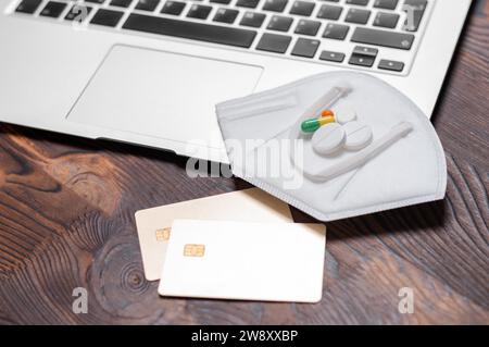 Image of laptop, bank gold card, pills and coronavirus protection equipment. Health insurance concept. The medicine. Mixed media Stock Photo