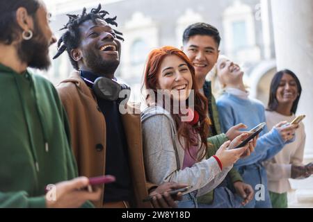 Multicultural friends laugh and chat in a city setting, sharing a joyful day. Stock Photo