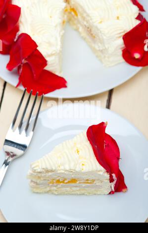 Whipped cream mango cake with red rose petals, food photography Stock Photo