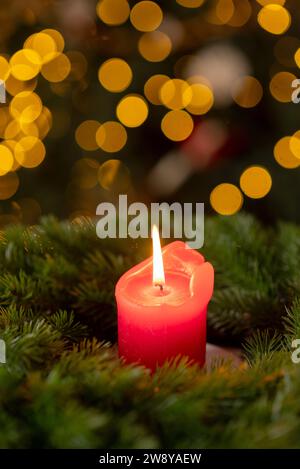 Decorated Advent wreath from fir branches with red burning candle on a wooden windowsill in the time before Christmas Stock Photo