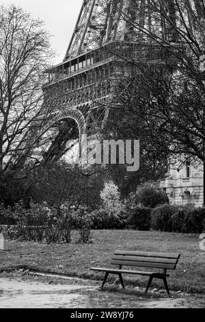 Empty public bench at the foot of the Eiffel Tower in Paris in black and white - France Stock Photo