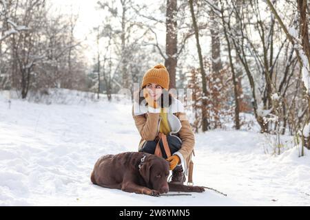 Woman with adorable Labrador Retriever dog in snowy park Stock Photo