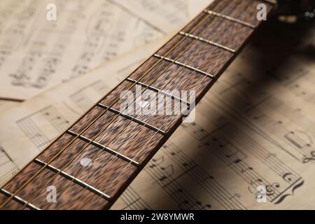 Guitar neck on paper sheets with music notes, closeup Stock Photo