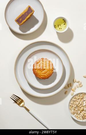 Traditional Chinese mid autumn festival, mooncakes on ceramic dishes and pumpkin seeds decorated on white background. Mid-Autumn Festival is also know Stock Photo