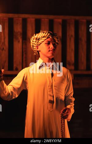 An Arabian man holding a fire torch in the front of a wooden house in the dark night Stock Photo