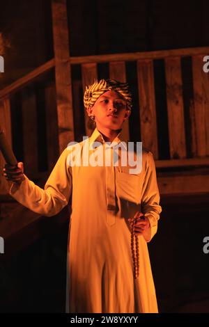 An Arabian man holding a fire torch in the front of a wooden house in the dark night Stock Photo