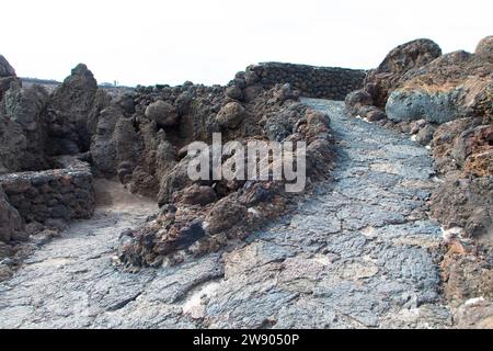 Hiking trail in Los Hervideros. Southwest coast, rugged volcanic landscape, caves and red lava hills. Lanzarote, Canary Islands, Spain Stock Photo