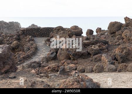 Hiking trail in Los Hervideros. Southwest coast, rugged volcanic landscape, caves and red lava hills. Lanzarote, Canary Islands, Spain Stock Photo