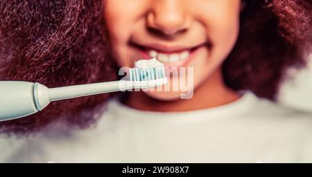 Little cute african american girl brushing her teeth. Healthy teeth. Small afro girl, toothbrush. Multiracial girl brushes her teeth an electric Stock Photo