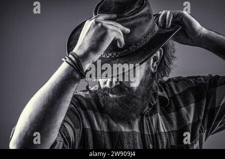 Cowboy hat. Portrait of young man wearing cowboy hat. Cowboys in hat. Handsome bearded macho. Black and white Stock Photo
