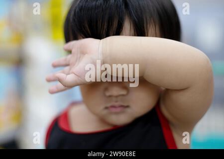 Cute boy  holding his right arm on the front as protecting from sun. Boy Holding His Arm In Front Of His Face. Stock Photo