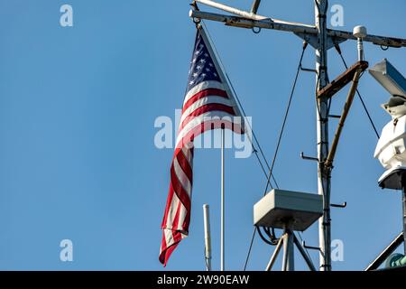 The great American flag, flying on the flagpole of an American ship, from where it is sighted informing of its nationality. Stock Photo