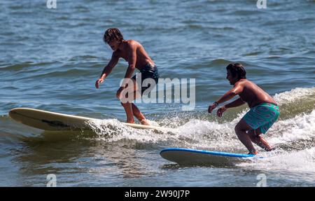 Gilgo Beach, New York, USA - 3 September 2023: A couple of people that are on surfboards in the water off the coast of Long Island at Gilgo Beach. Stock Photo