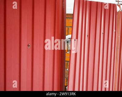 A torn fragment of a metal fence from a profiled sheet Stock Photo