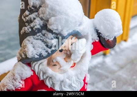 Close-up view of snow-covered gnome's face standing outside near entrance to house. Stock Photo