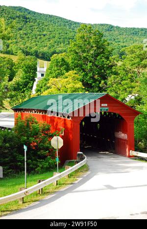 The Arlington Covered Bridge in rural Vermont leads to a small town and white steeple church Stock Photo