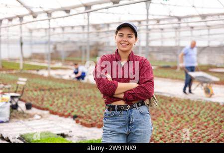Young woman worker posing joyfully in greenhouse Stock Photo