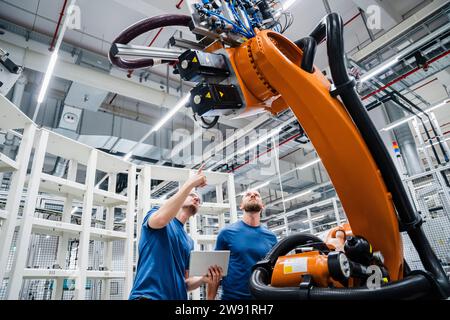 Two technicians examining industrial robot in a factory Stock Photo