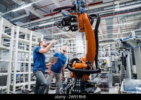 Two technicians examining industrial robot in a factory Stock Photo