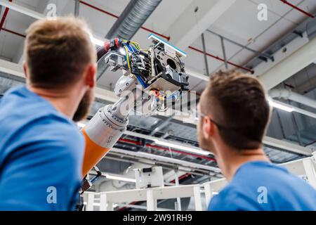 Two technicians examining industrial robot in a factory Stock Photo