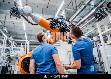 Two technicians examining industrial robot in a factory Stock Photo