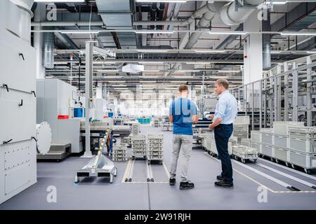 Rear view of businessman and employee standing in a factory Stock Photo