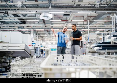 Two colleagues with digital tablet talking in a factory Stock Photo