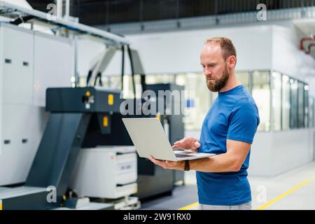 Technician using laptop on shop floor in a factory Stock Photo
