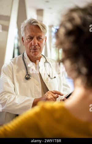 Senior doctor discussing with young woman in hospital Stock Photo