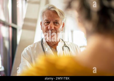 Smiling senior doctor talking to woman Stock Photo