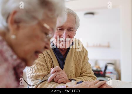 Smiling senior man with woman reading book and holding hands at home Stock Photo