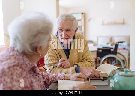 Senior man talking to woman sitting at table Stock Photo