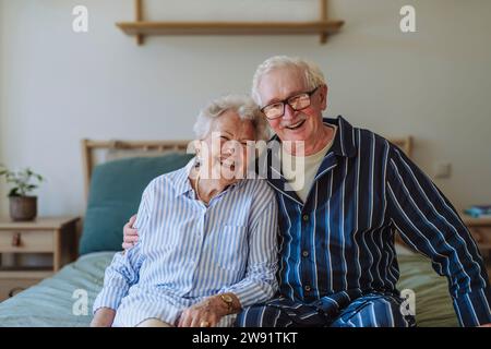 Happy senior couple sitting on bed together at home Stock Photo