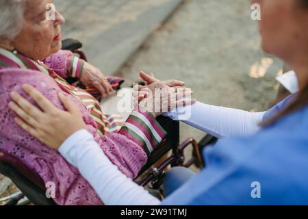 Healthcare worker holding hands and consoling senior woman Stock Photo
